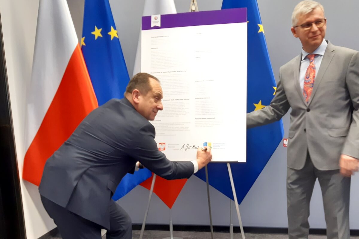 Minister Andrzej Gut-Mostowy podpisuje Dekalog OSAT, po prawej Marcin Wujec
